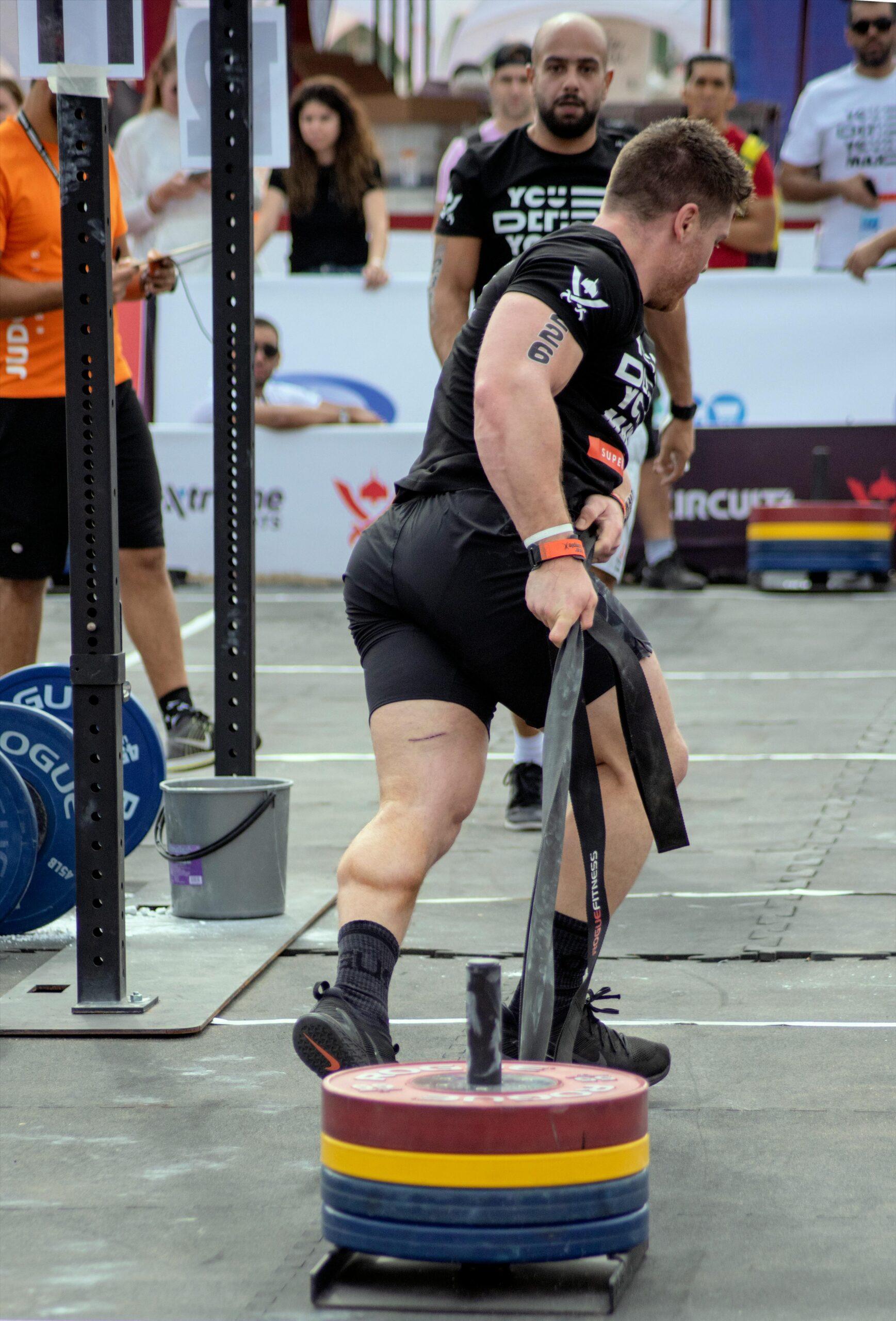 Athlete pulls heavy weights in a strongman competition outdoors.
